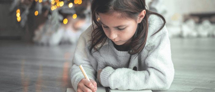 Niña escribiendo una carta a los Reyes Magos en Navidad