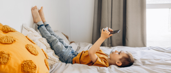 niño jugando con pantalla en su cama
